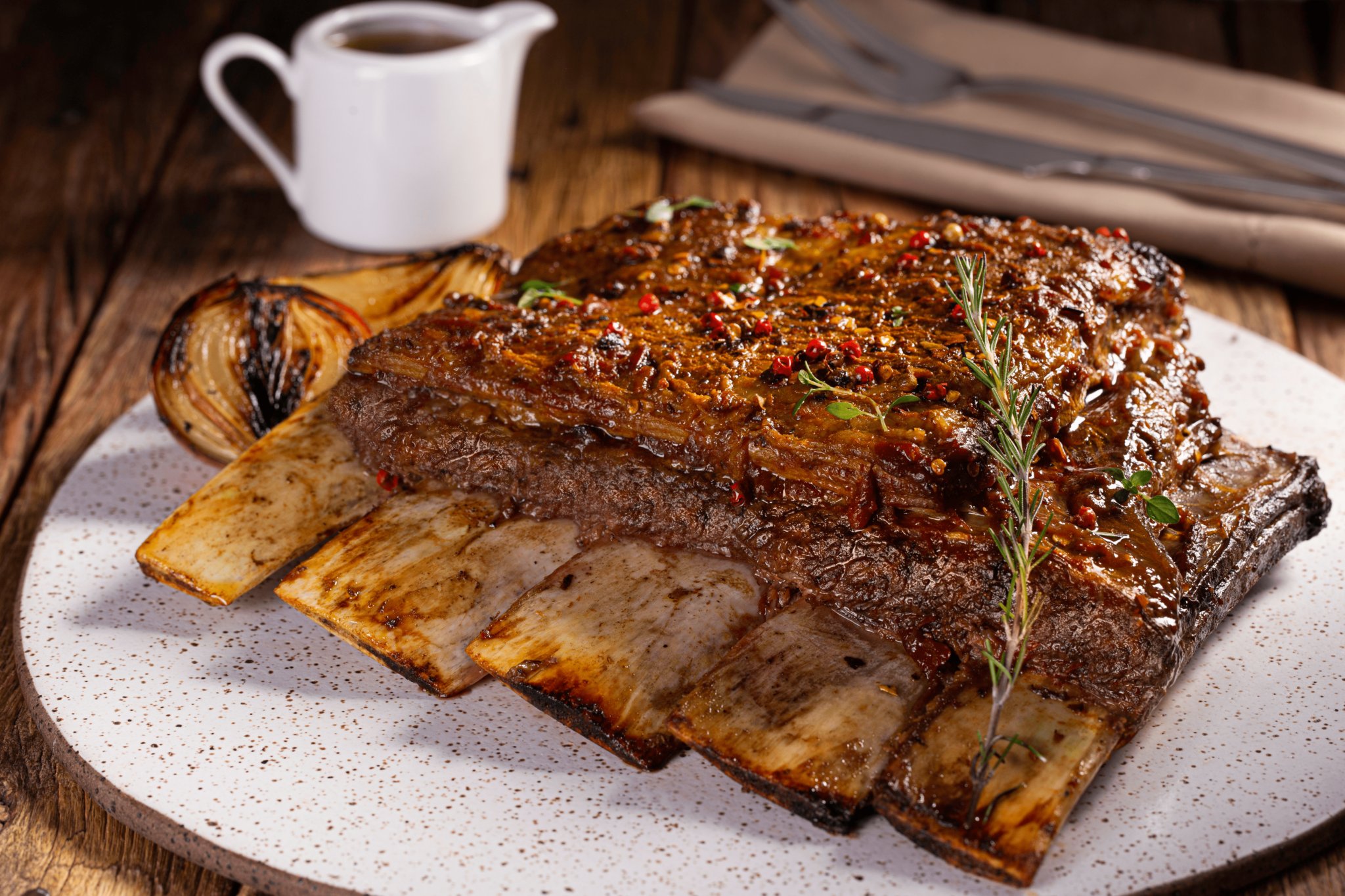 Costela assada no bafo com cebola, temperos e alecrim, servida sobre tábua de madeira